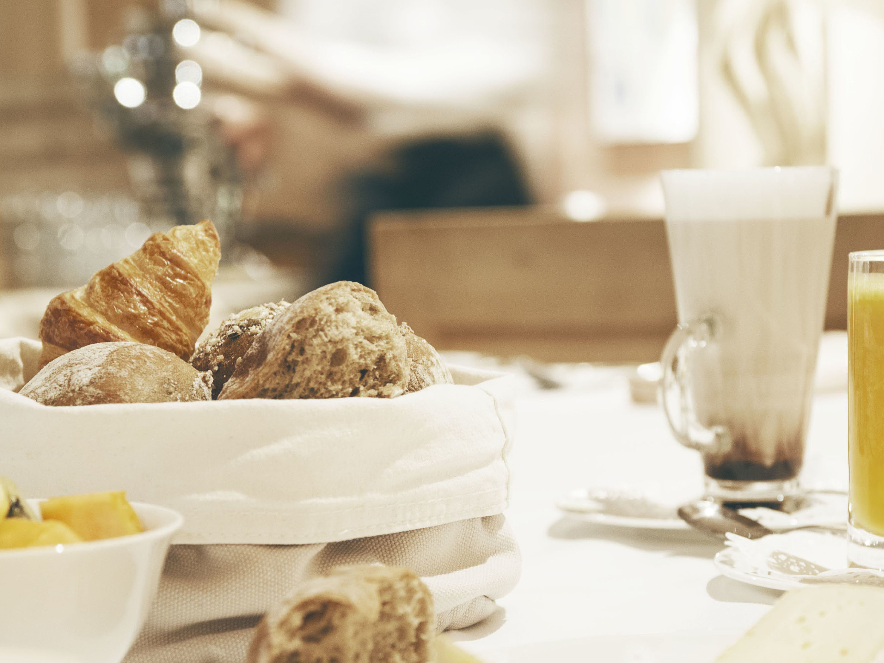 Frühstückstisch mit Brot und Saft Frühstückstisch mit Brotkorb, Orangensaft und Latte Macchiato.